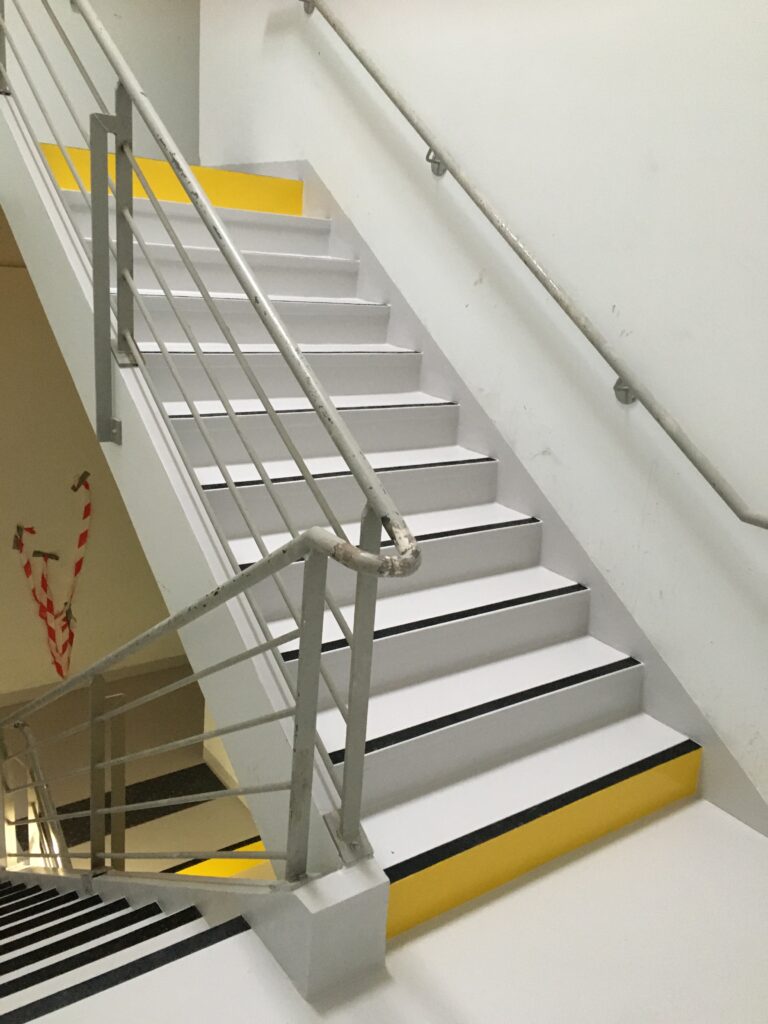 Application de résine sur escaliers aux normes d'accessibilité PMR et dalles podotactiles.